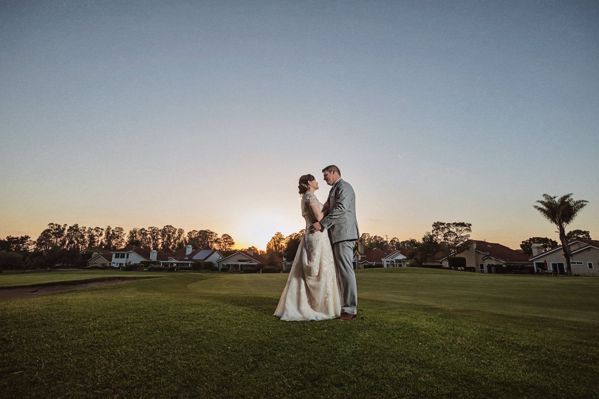 Amanda and Joseph standing together on the golf course at sunset
