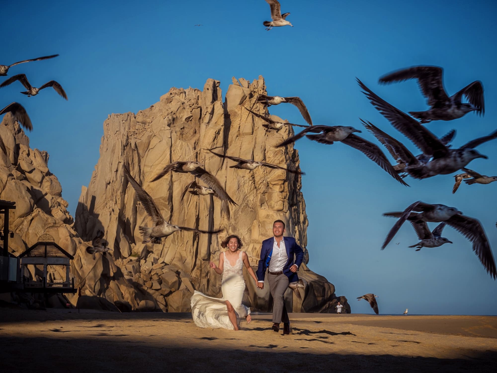 Kirsten and Jolan among the granite rocks at Land's End in Cabo San Lucas as pelicans take flight around them, photographed by Michael Anthony Photography