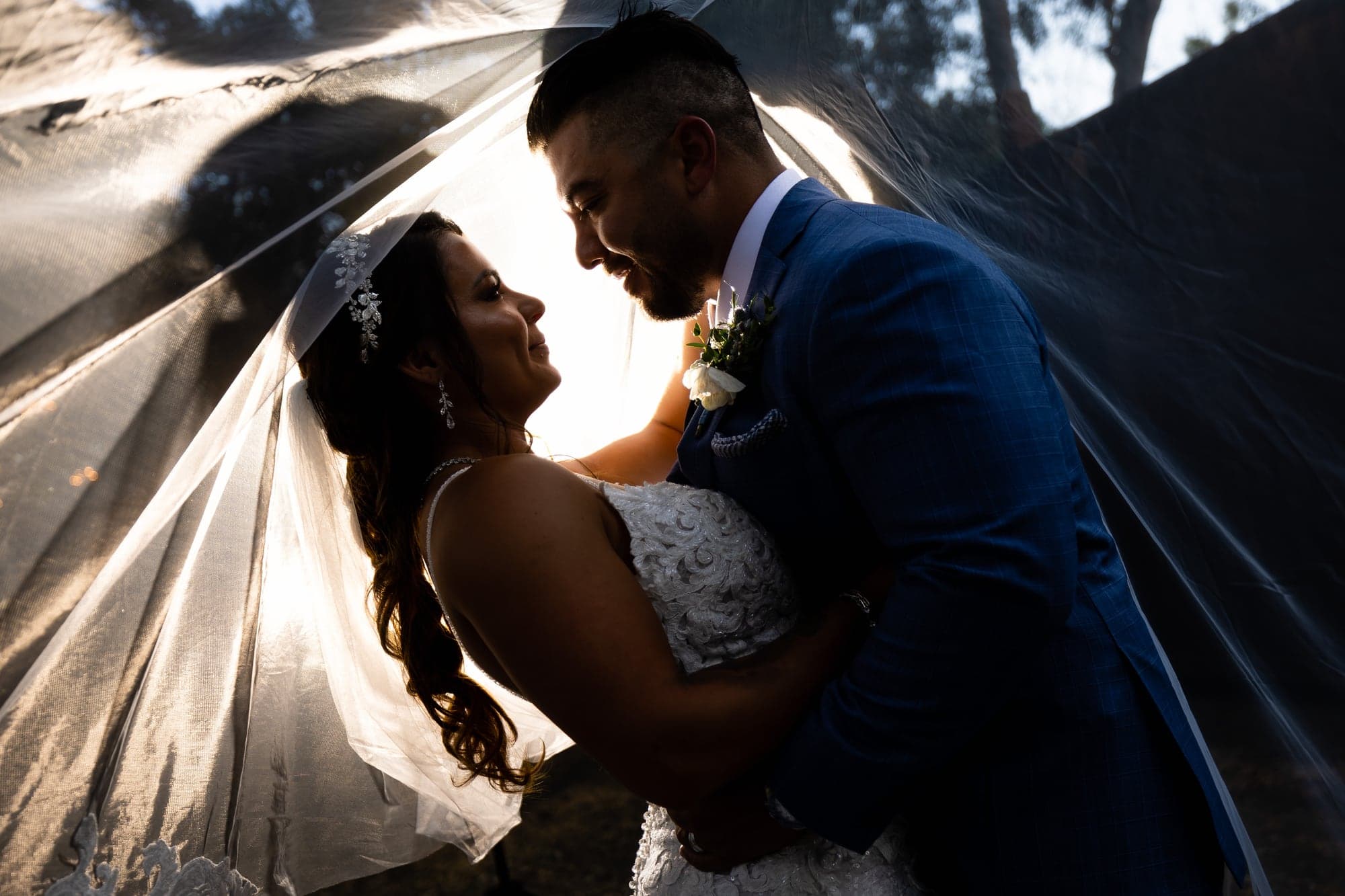 Arthur and Mazl sharing a backlit portrait beneath her wedding veil at Calamigos Ranch