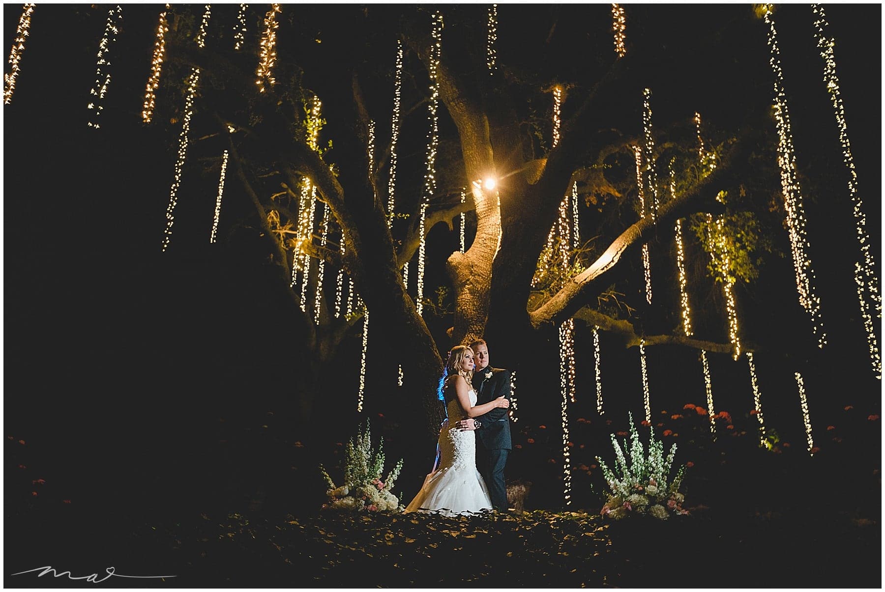 Brooke and Kyle beneath hanging lights at Calamigos Ranch