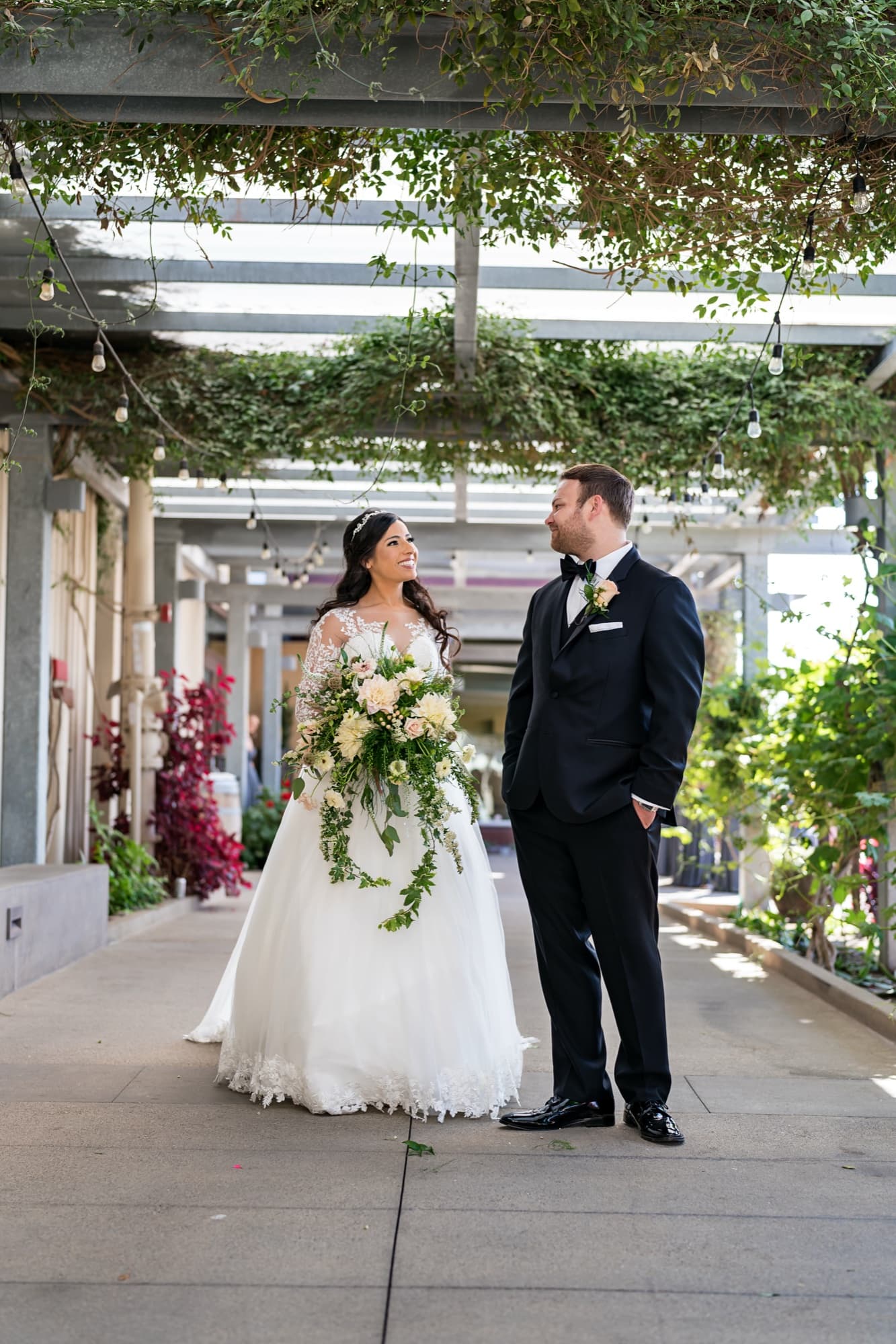 Tania and Cole standing together in the vine-draped breezeway at Callaway Vineyard and Winery in Temecula, photographed by Michael Anthony Photography