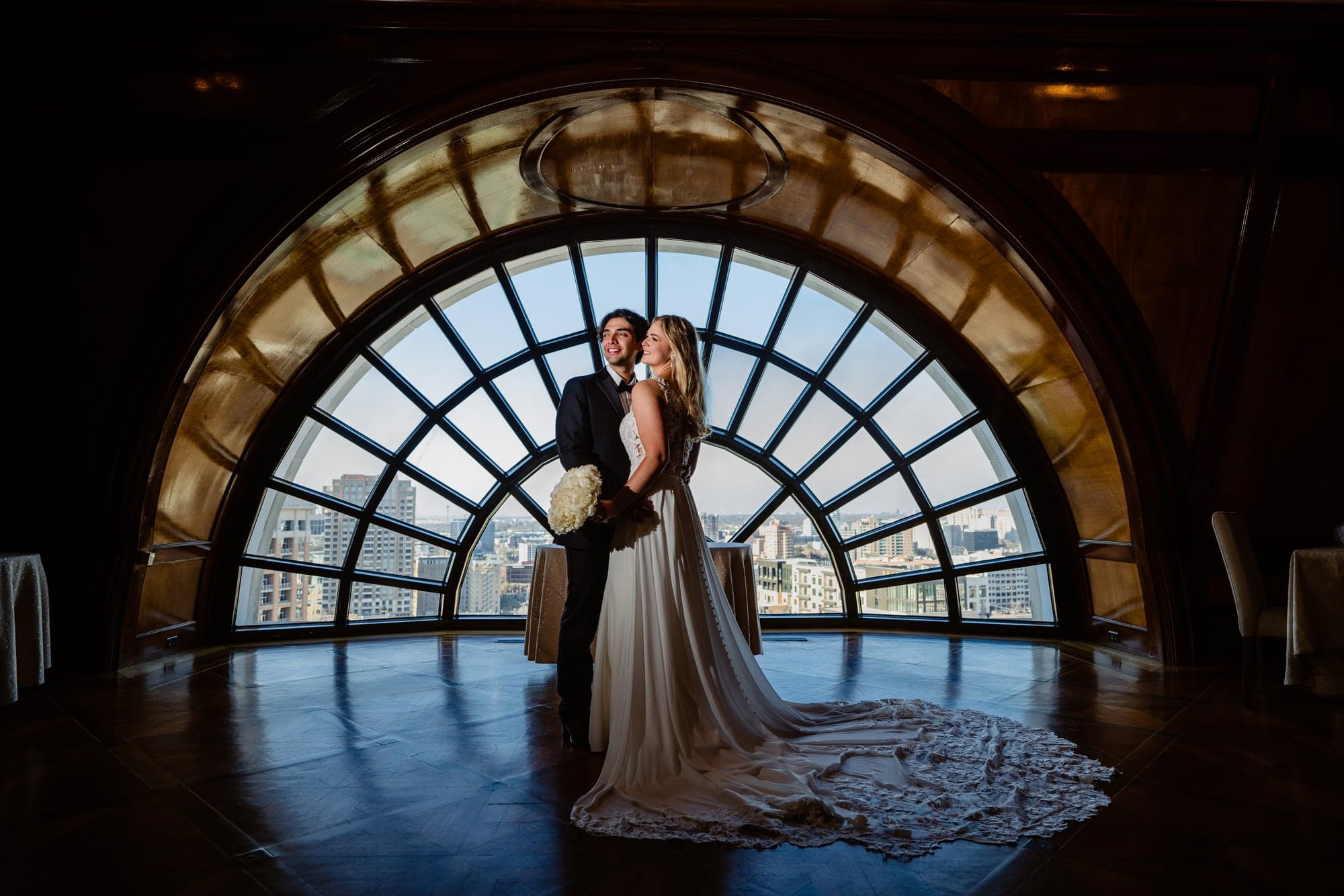 Lindsay and Jayton standing beneath a glowing circular window during their downtown Dallas wedding