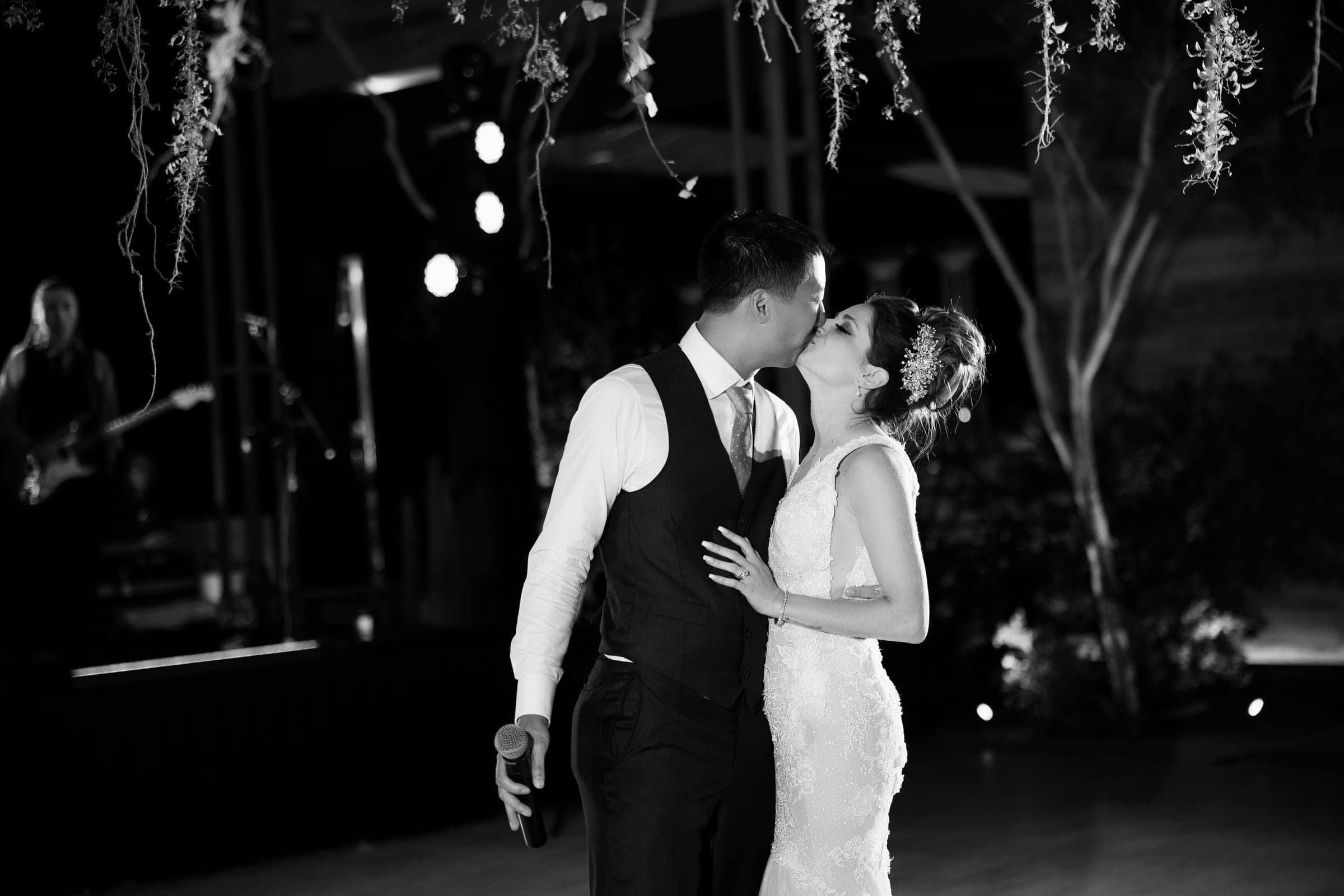 A couple dancing close in a darkened reception room lit only by the venue's own low light, the kind of frame a fixed film speed cannot hold.