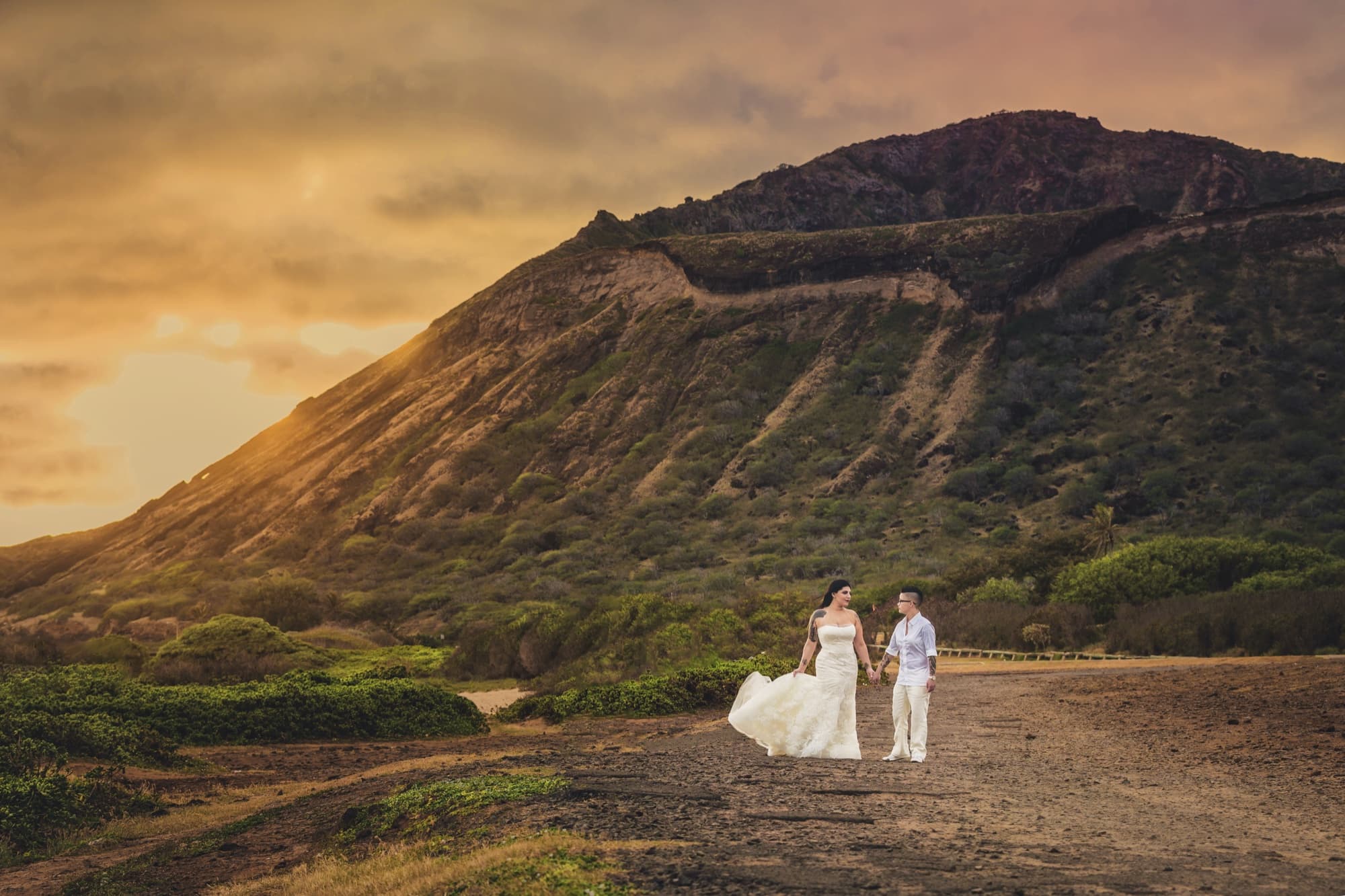 Amanda and Shauna holding hands in the golden light below Koko Head crater on Oahu at sunset, photographed by Michael Anthony Photography