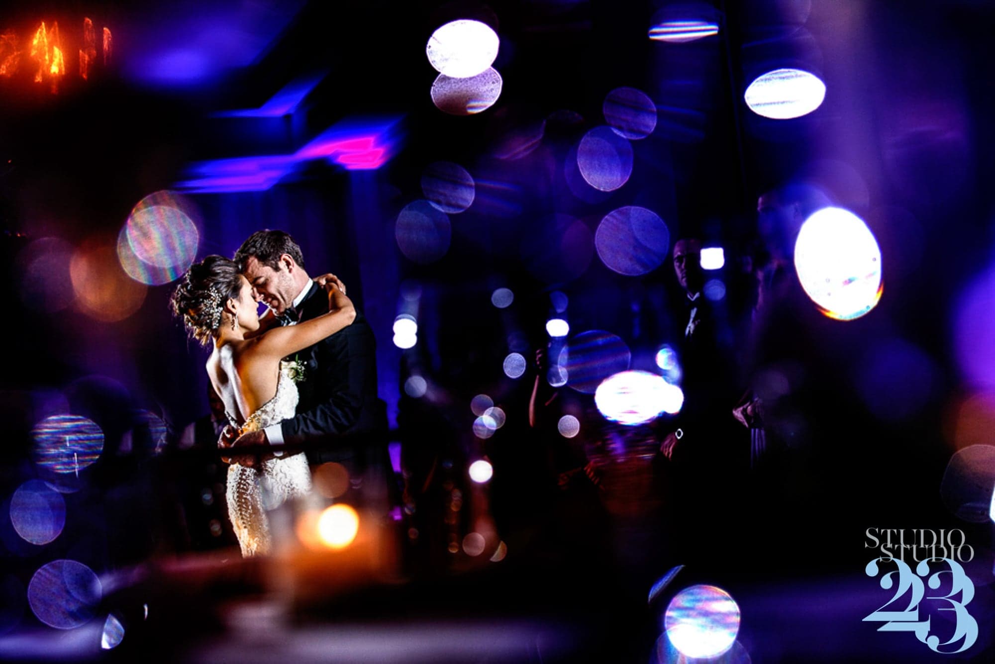 Nate and his bride dancing beneath colorful reception lights