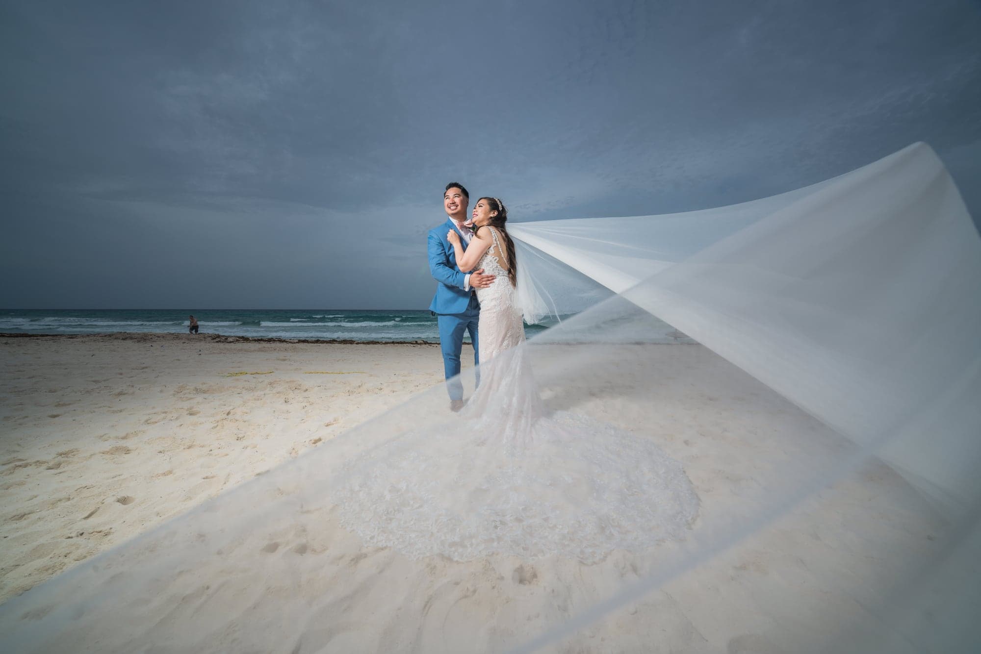 Jilliene and Avery beneath a flowing veil on the Cancun beach