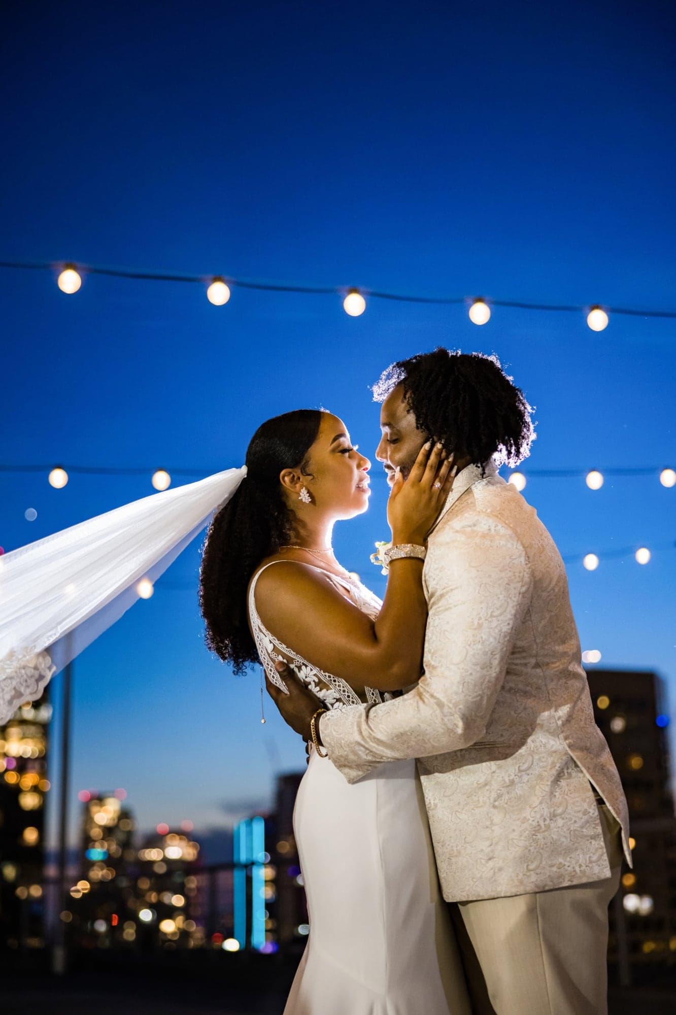 Tyrannie and Kalen embracing beneath string lights on the Los Angeles Athletic Club rooftop at blue hour, photographed by Michael Anthony Photography