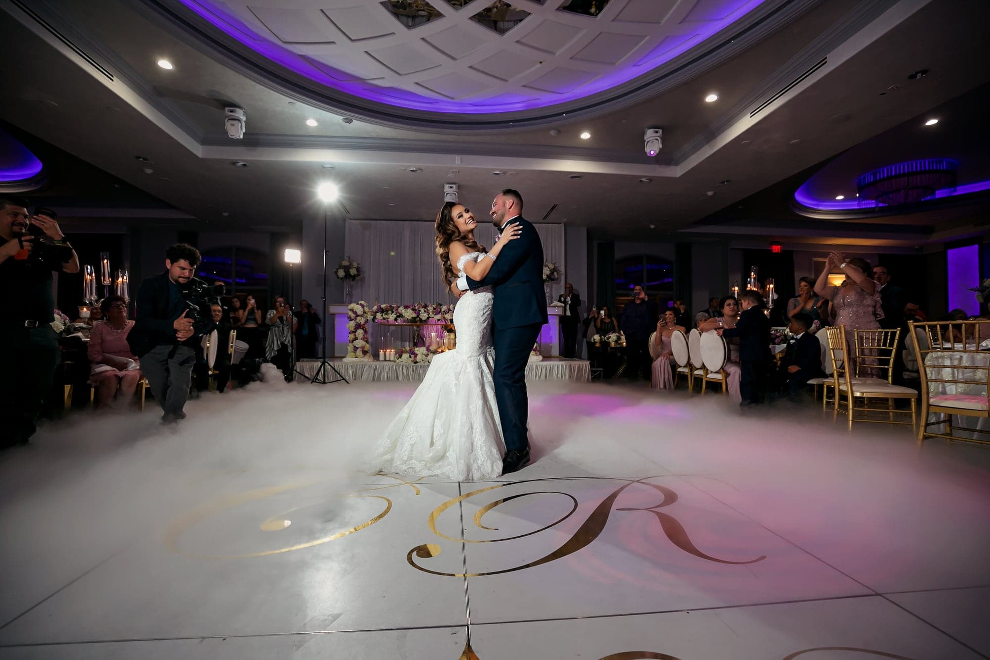 Wedding couple dancing beneath purple ballroom lights