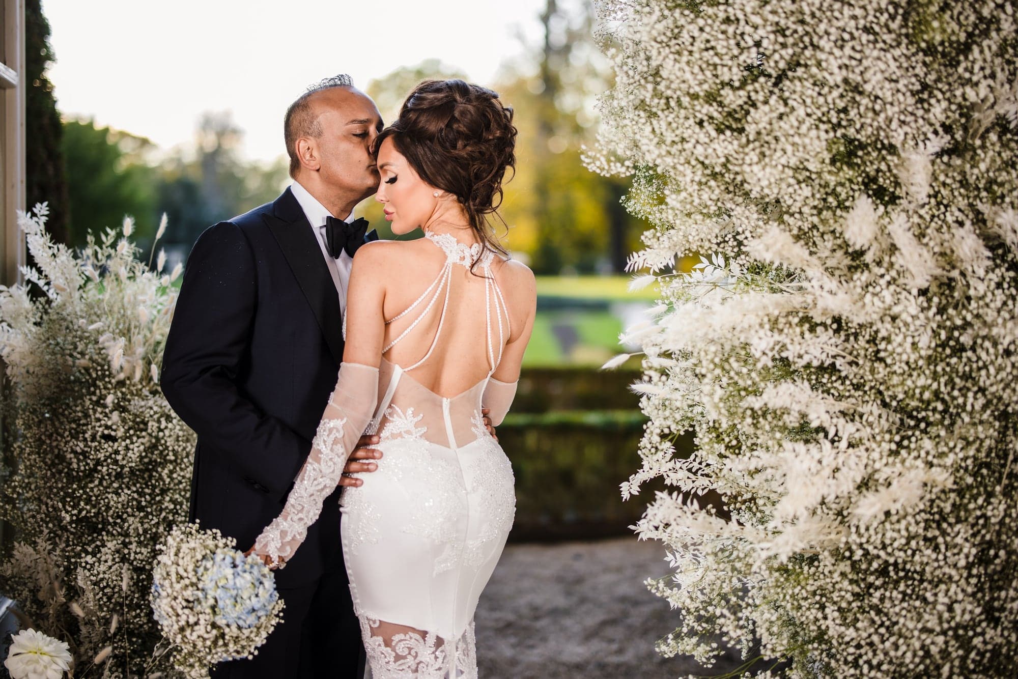 Wedding couple surrounded by white flowers at a luxury estate