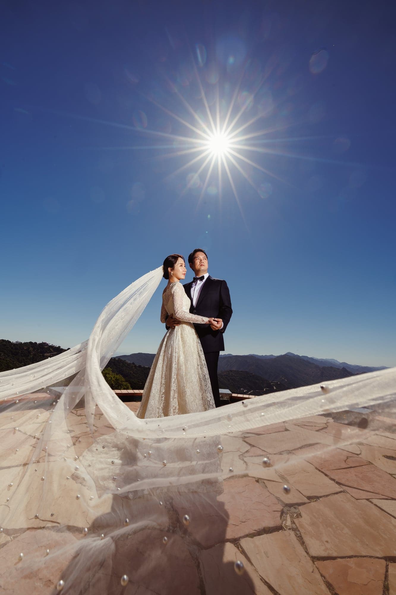 Lauren and Lee standing together on a Malibu mountaintop beneath a deep blue sky