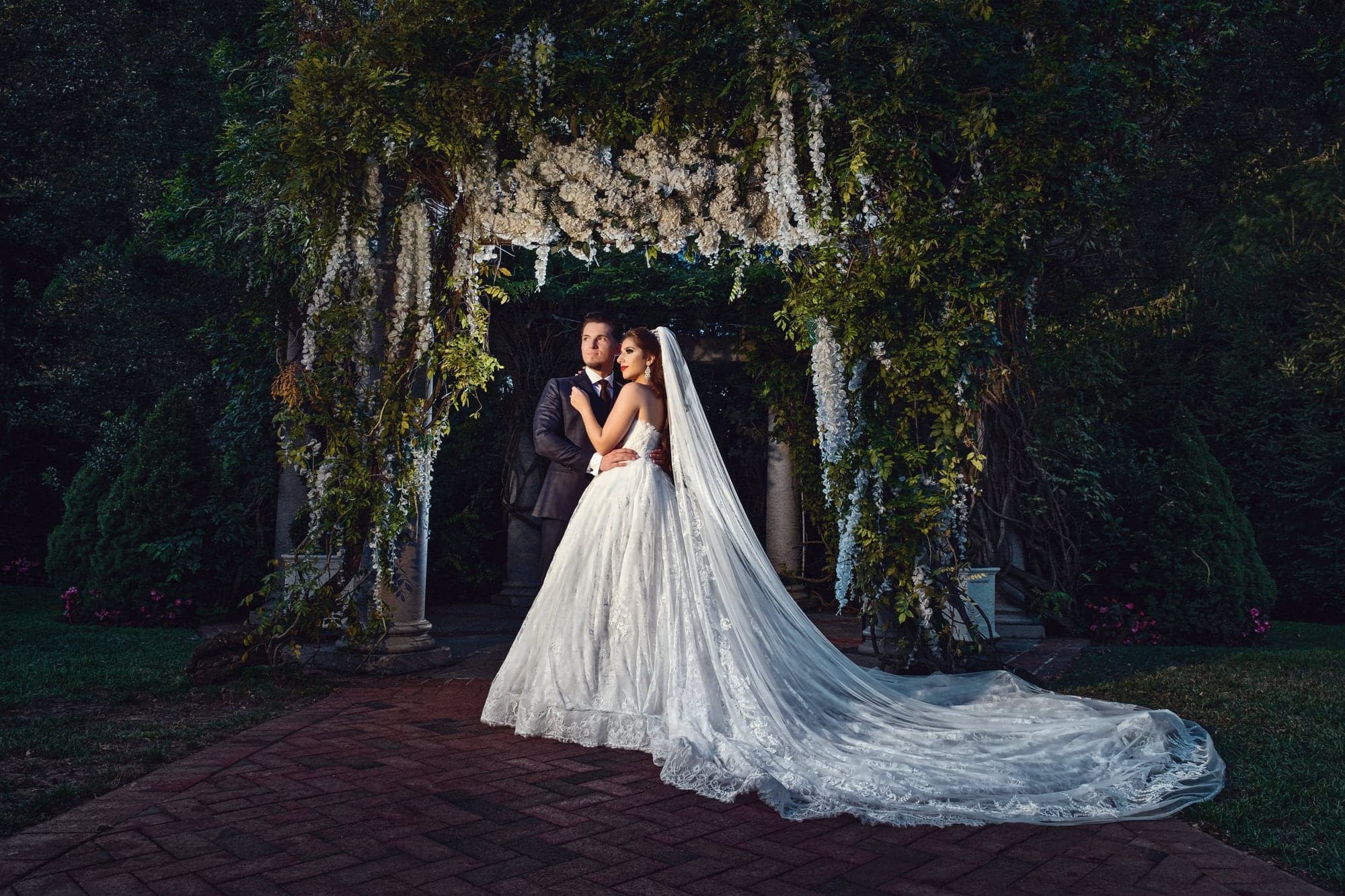 Jasmina and Admir beneath a long veil in a New York garden