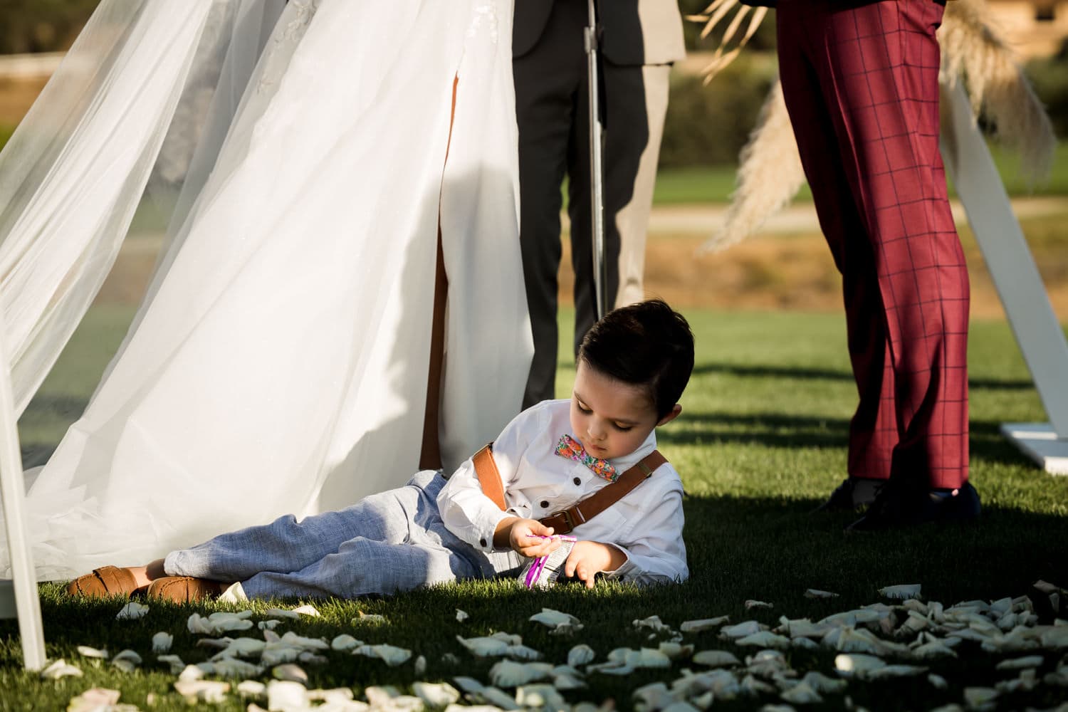 Amber and Robert beneath a triangle arch dressed in pampas grass on the fairway at The Oaks Club at Valencia, her veil streaming under a deep blue sky, photographed by Michael Anthony Photography