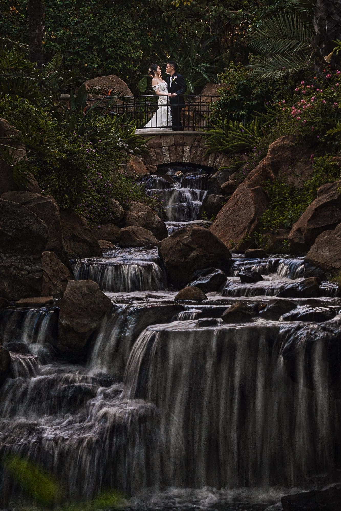 Wedding couple standing together beside a waterfall at Rancho Las Lomas