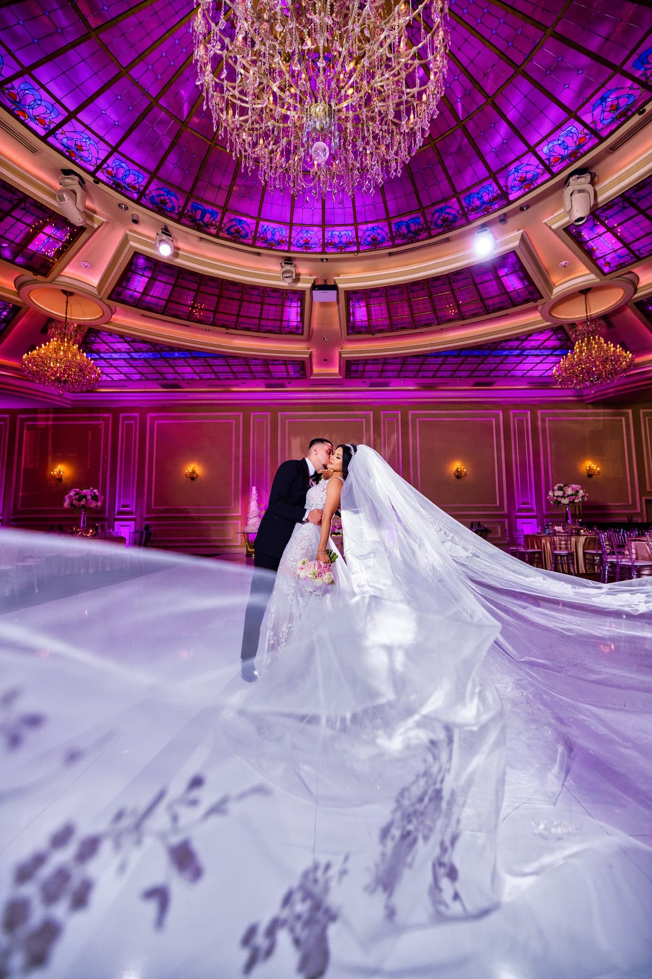 Marilou and Rafic kissing in the illuminated Taglyan Complex ballroom