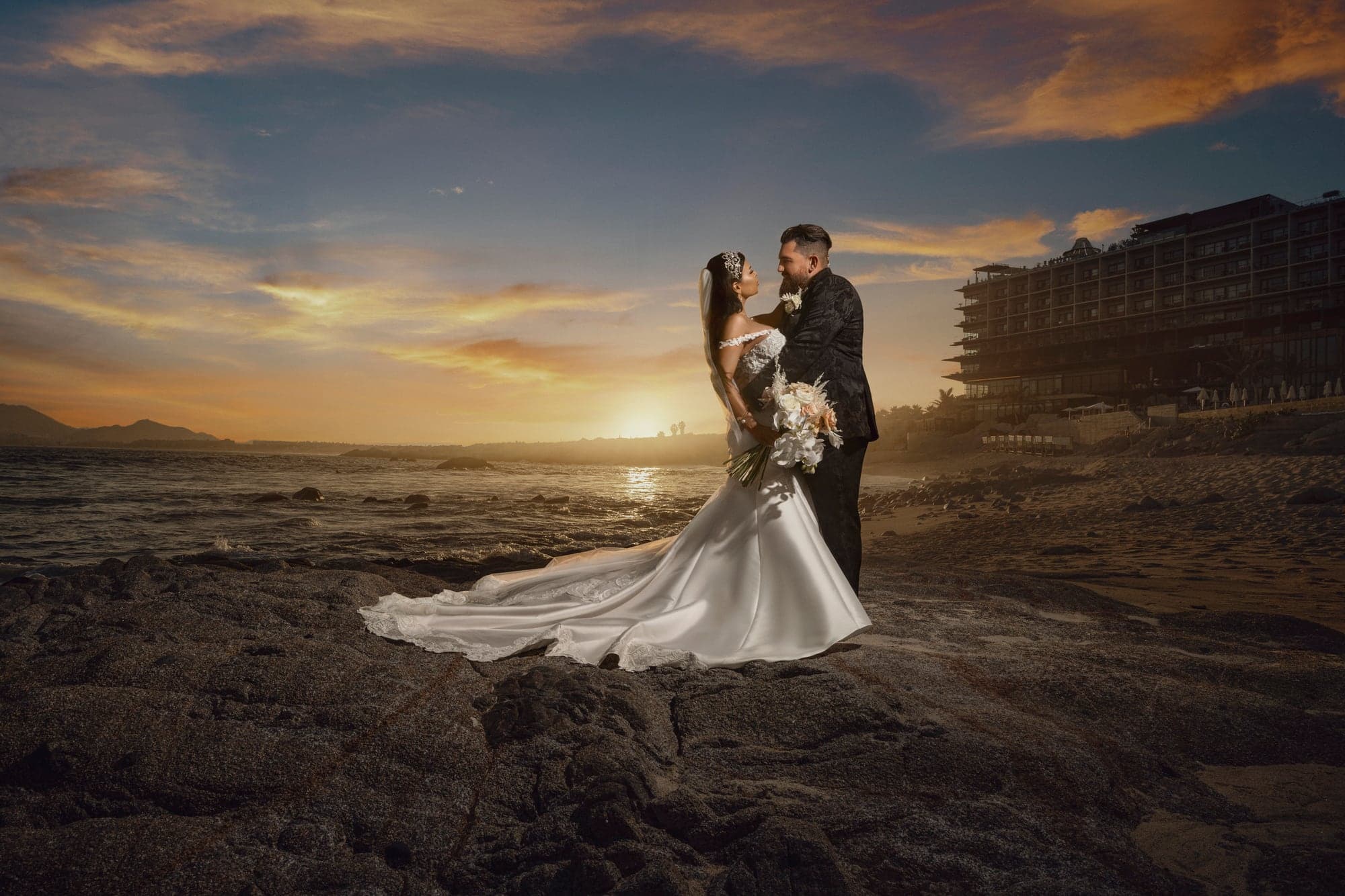 Bryanna and Justin standing together in the Cabo desert beneath a dramatic sunset sky, photographed by Michael Anthony Photography
