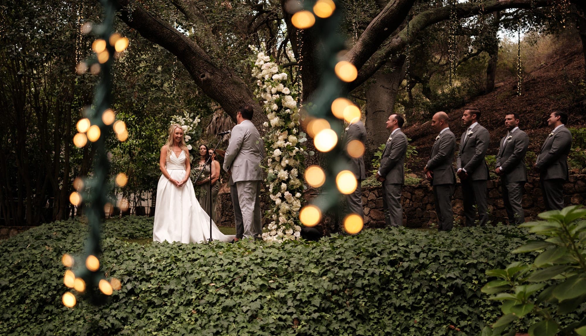 A wedding couple beneath towering trees at a lush Malibu ranch, evoking a Calamigos Ranch ceremony