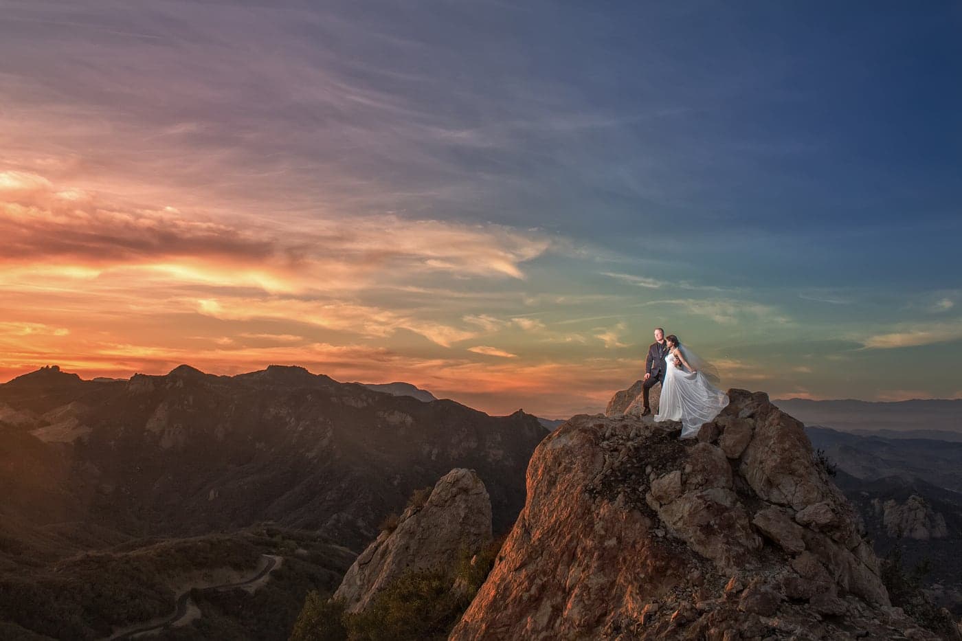 A wedding couple framed against grand architecture at dusk, evoking a large resort celebration