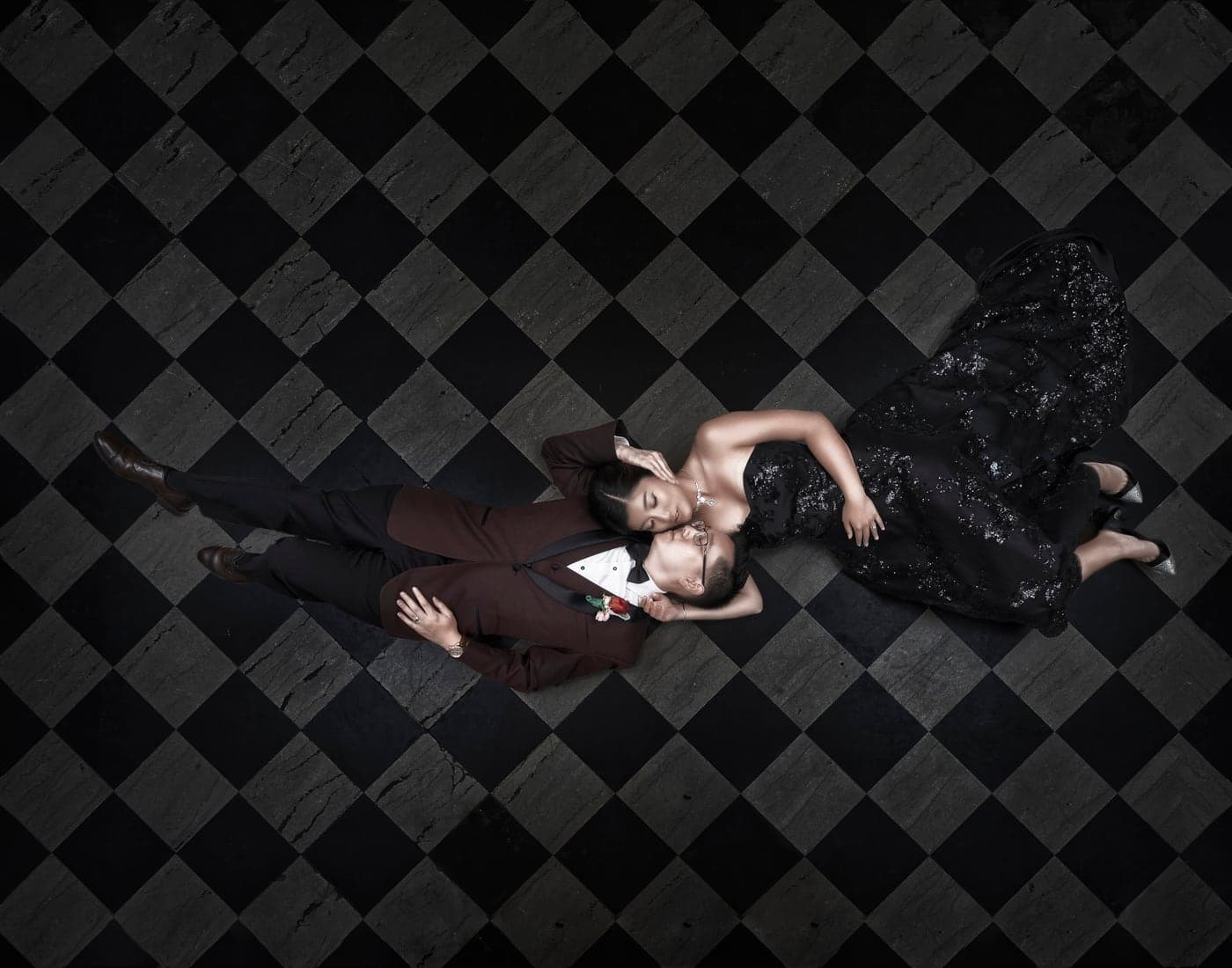 A formally dressed couple photographed against a graphic black-and-white floor