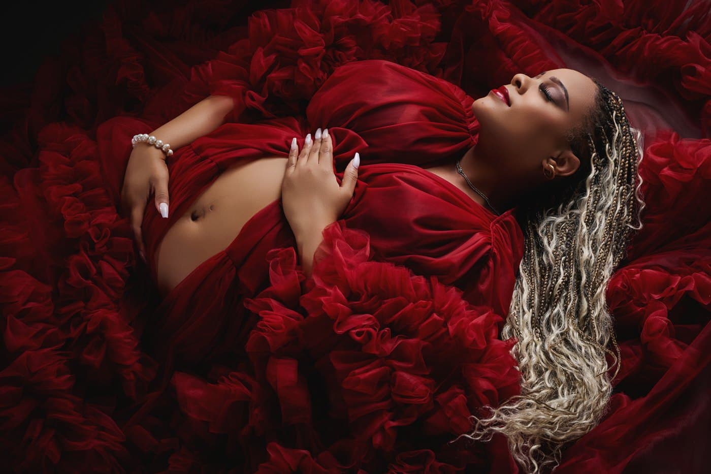 Fine-art maternity portrait in a burgundy gown with a fanned floral train