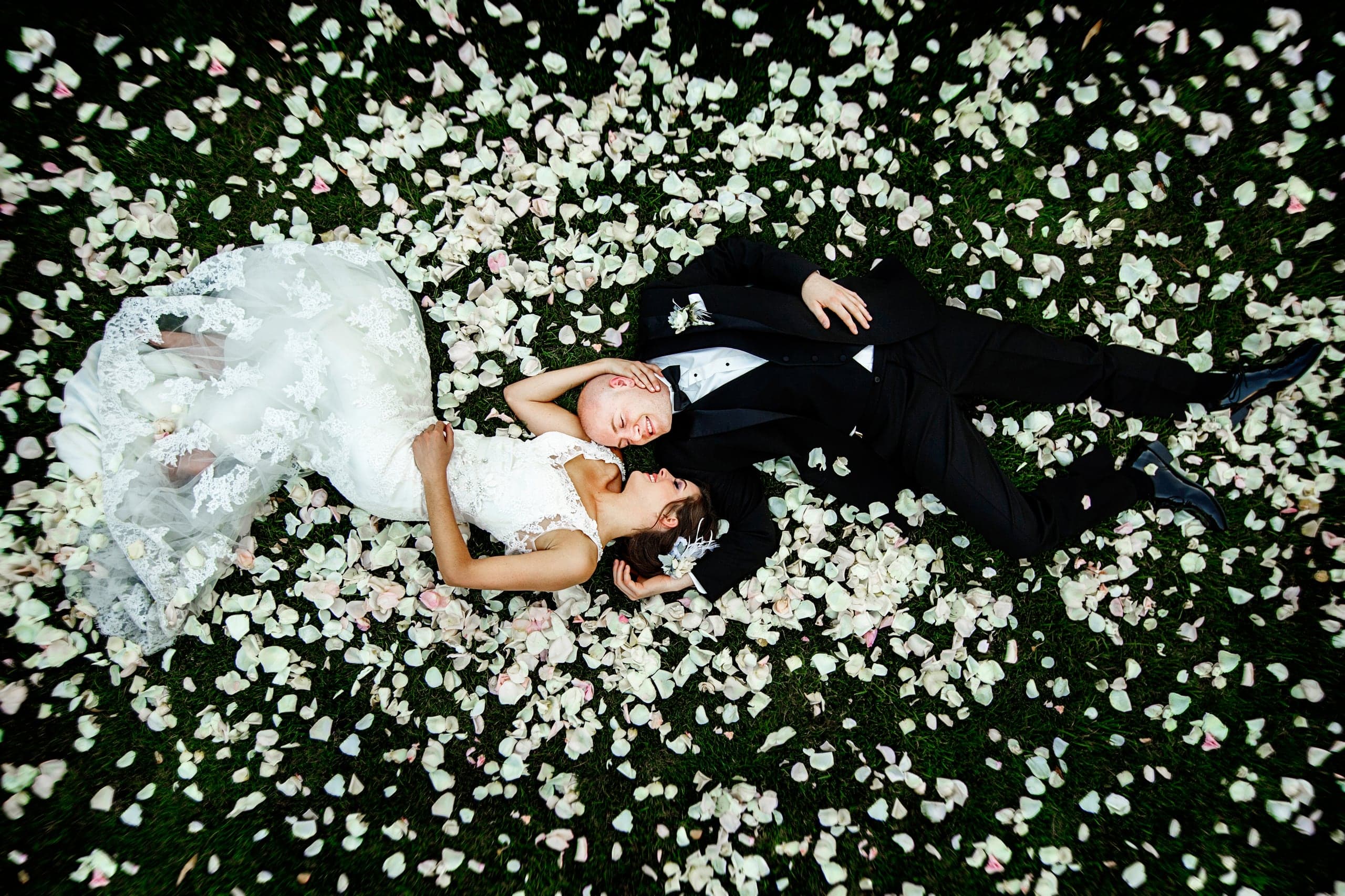 Bride and groom lying in a field of white petals