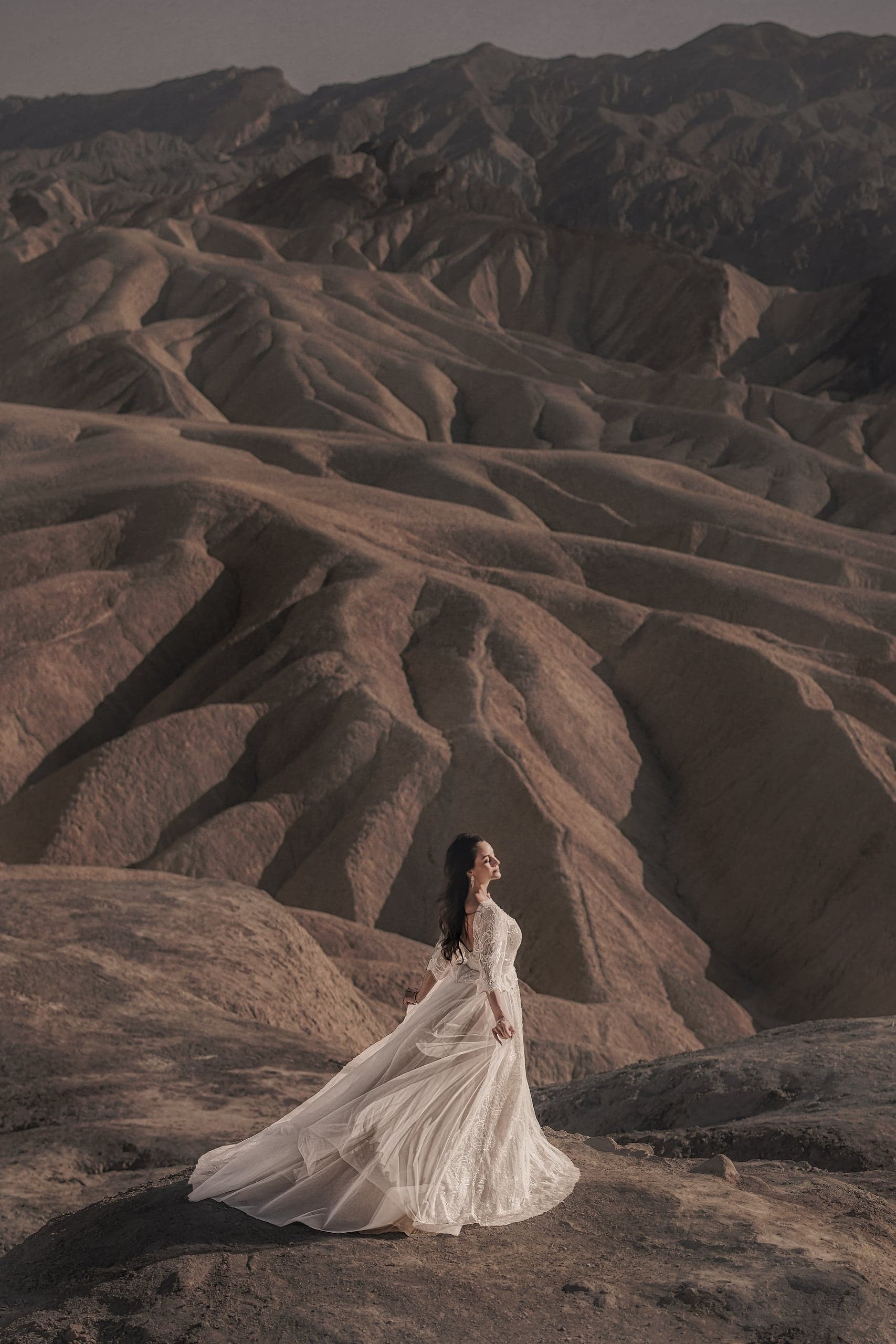 Bride on volcanic rock, gown trailing